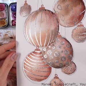 Op de afbeelding: Een aquarel schilderij van kerstballen met zilveren glitter accenten. De kerstballen zijn geschilderd in tinten bruin en roze.