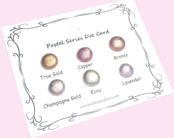 May include: A white card with six pastel-colored paint dots: True Gold, Copper, Bronze, Champagne Gold, Ecru, and Lavender. The card is labeled "Pastel Series Dot Card" with a decorative border and the website www.mabwatercolours.com.