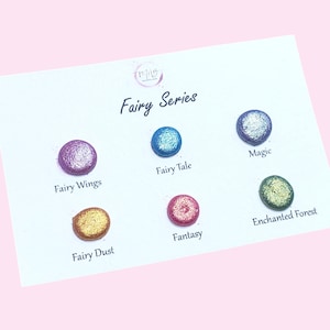Pode incluir: Um cartão branco com as palavras "Fairy Series" e seis amostras de tinta redondas e coloridas. As amostras são rotuladas como "Fairy Wings", "Fairy Tale", "Magic", "Fairy Dust", "Fantasy" e "Enchanted Forest."