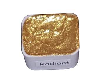 Puede incluir: Un pequeño recipiente cuadrado de pintura metálica dorada con la palabra "Radiant" impresa en la etiqueta.