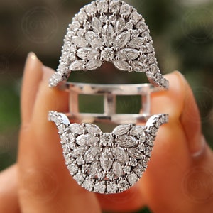 May include: A silver ring with a large, intricate design of small, clear diamonds. The ring is made up of two pieces that fit together.