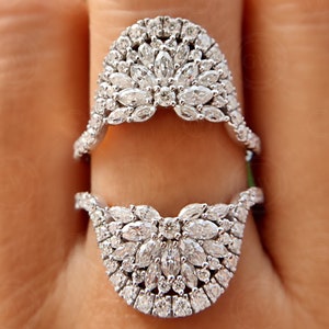 May include: A pair of silver rings with a unique design featuring a cluster of small, clear diamonds set in a delicate, curved shape. The rings are designed to be worn together, creating a beautiful and intricate look.