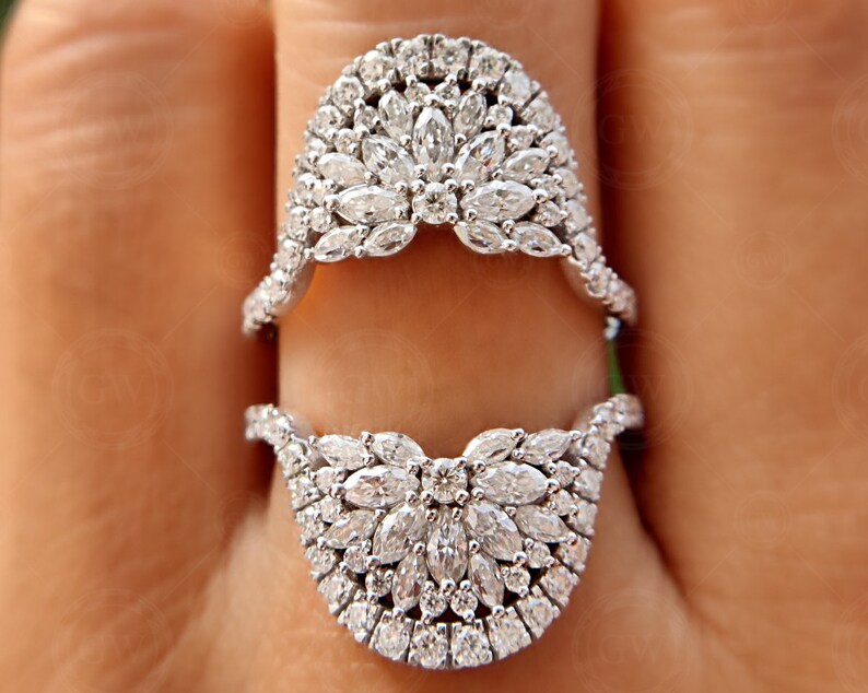 May include: A pair of silver rings with a unique design featuring a cluster of small, clear diamonds set in a delicate, curved shape. The rings are designed to be worn together, creating a beautiful and intricate look.
