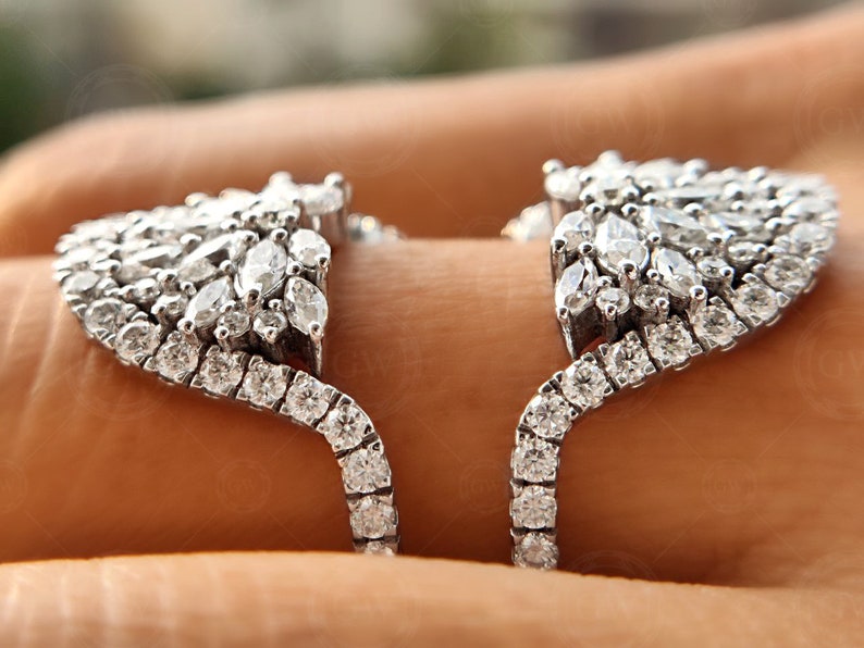 May include: A silver ring with a large, intricate design of pave-set diamonds. The ring is open in the back and has a curved shape.