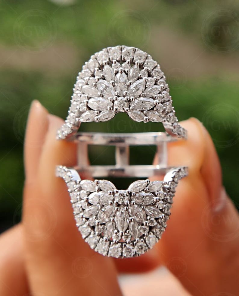 May include: A silver ring with a large, intricate design of small diamonds set in a floral pattern. The ring is split into two parts, with the top part sitting on top of the bottom part.