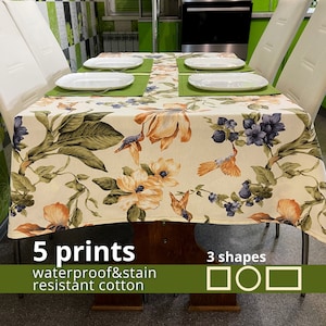 Puede incluir: Un mantel blanco con un patrón floral que presenta pájaros y flores. El mantel es impermeable y resistente a las manchas. Está hecho de algodón. El texto "5 prints" y "waterproof & stain resistant cotton" es visible en la imagen. Se muestran tres formas debajo del texto: un cuadrado, un círculo y un rectángulo.