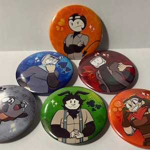 Puede incluir: Seis chapas redondas con ilustraciones de personajes de dibujos animados. Los botones muestran varios personajes en distintos esquemas de color, incluyendo naranja, azul, rojo, gris, verde y un naranja-marrón cálido con patrones gráficos.