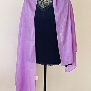 May include: A light purple sheer scarf draped over a black mannequin. The scarf is made of a lightweight fabric and has a soft, flowing drape.