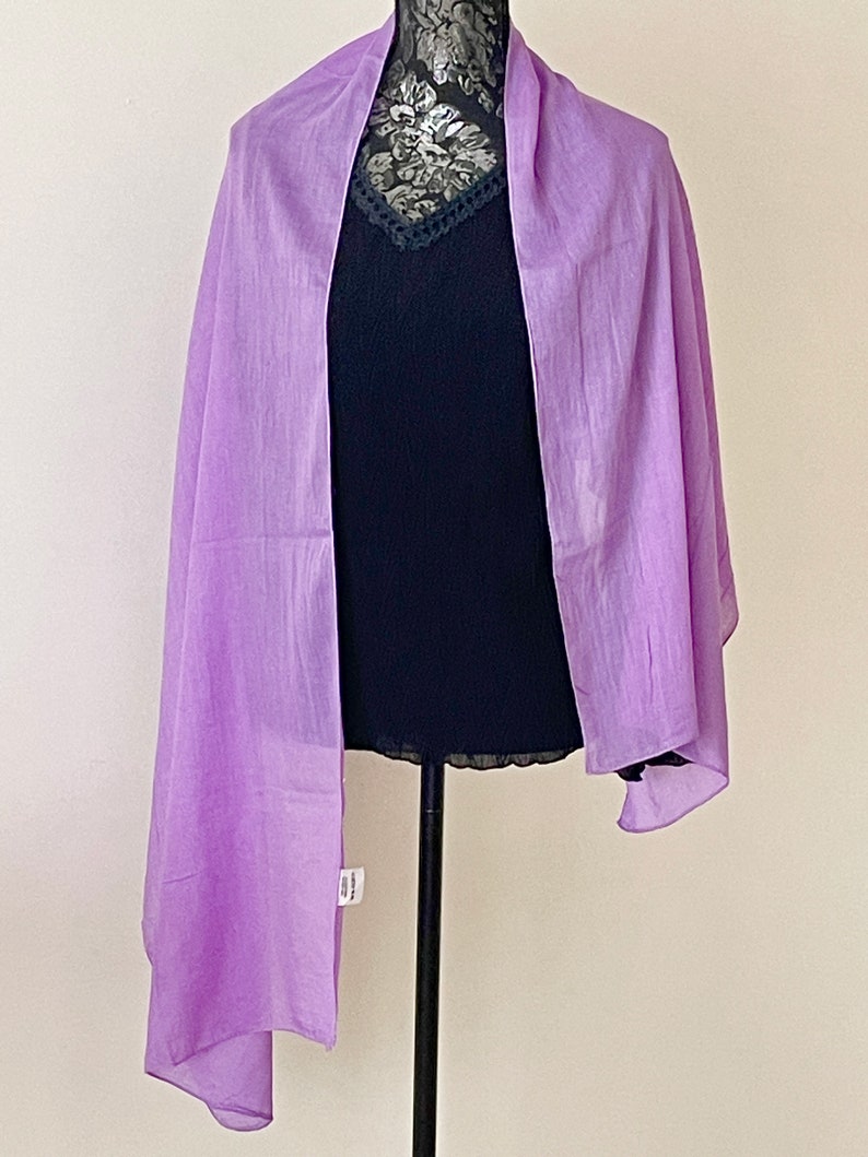 May include: A light purple sheer scarf draped over a black mannequin. The scarf is made of a lightweight fabric and has a soft, flowing drape.