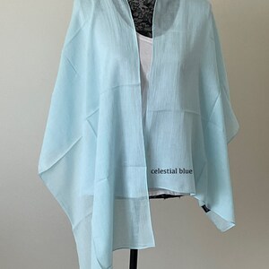 May include: A light blue sheer scarf draped over a mannequin. The scarf is made of a lightweight fabric and has a slightly textured finish. The text "celestial blue" is visible on the scarf.