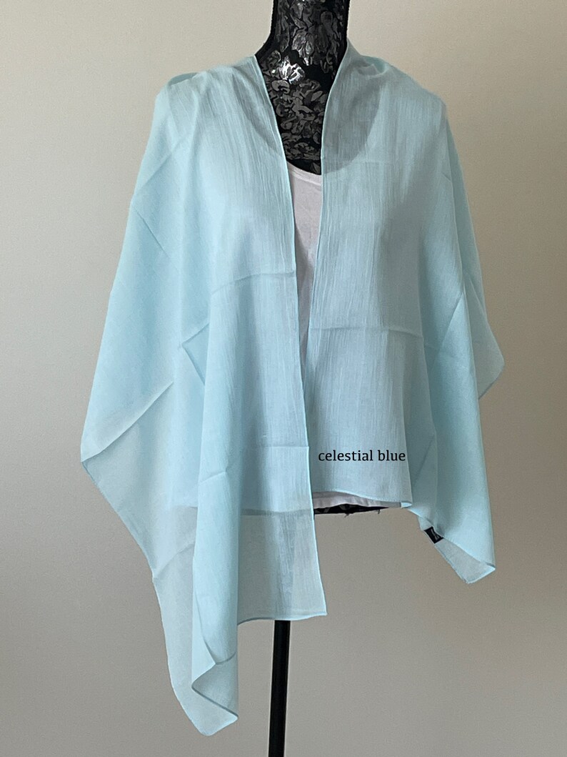 May include: A light blue sheer scarf draped over a mannequin. The scarf is made of a lightweight fabric and has a slightly textured finish. The text "celestial blue" is visible on the scarf.