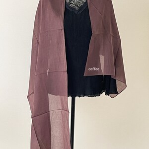 May include: A mauve sheer scarf draped over a black top. The scarf is made of a lightweight fabric and has a flowing, elegant look.