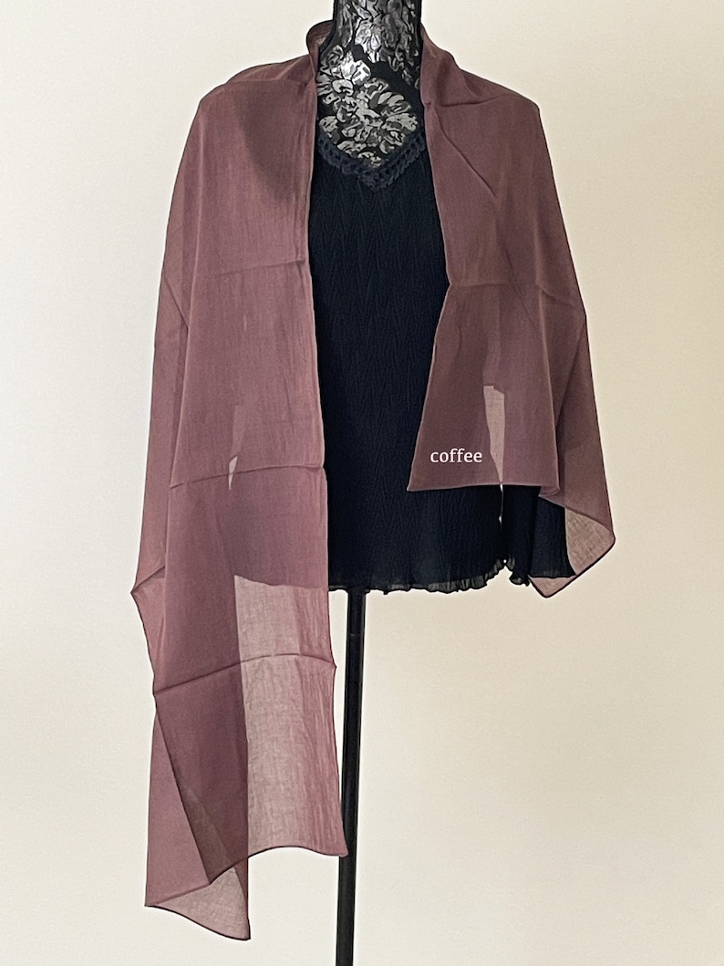 May include: A mauve sheer scarf draped over a black top. The scarf is made of a lightweight fabric and has a flowing, elegant look.