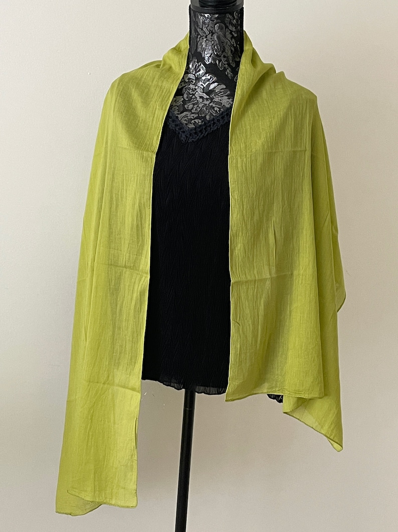 May include: A lime green scarf draped over a black mannequin. The scarf is made of a soft, lightweight fabric.