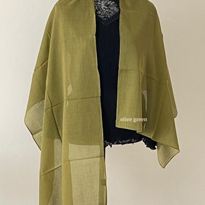 May include: Olive green scarf with a geometric pattern. The scarf is draped over a mannequin.
