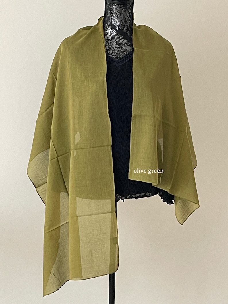 May include: Olive green scarf with a geometric pattern. The scarf is draped over a mannequin.