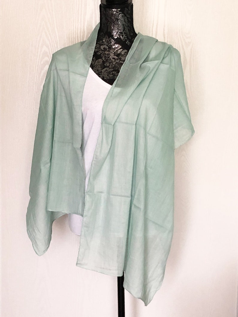 May include: A light green scarf draped over a mannequin. The scarf is made of a soft, lightweight fabric.