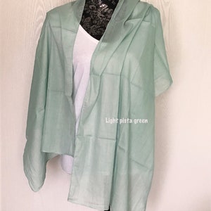 May include: A light pistachio green scarf draped over a mannequin. The scarf is made of a soft, lightweight fabric.