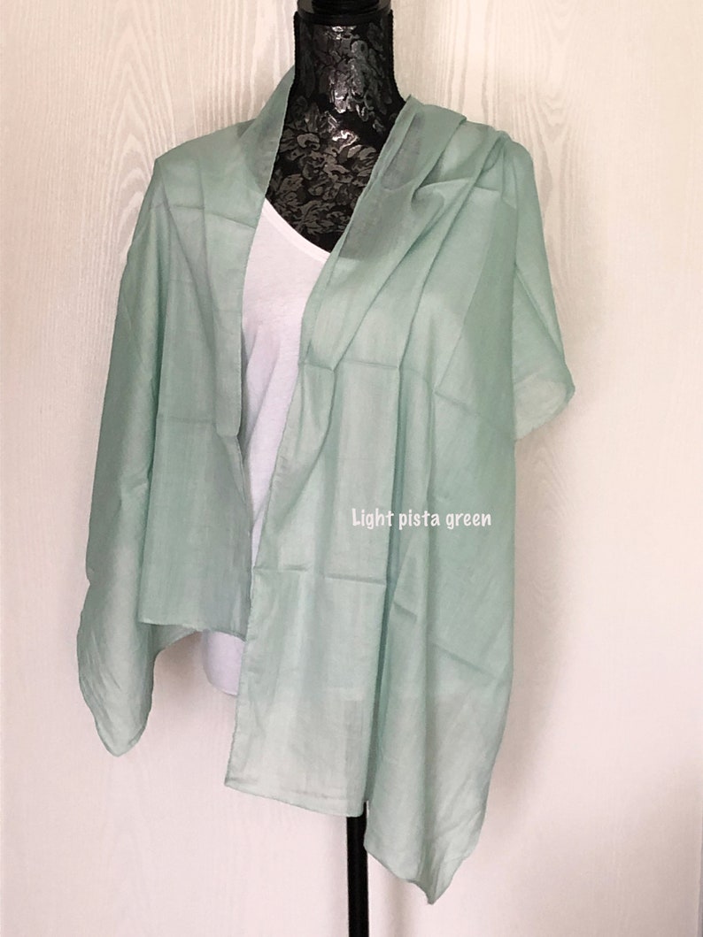 May include: A light pistachio green scarf draped over a mannequin. The scarf is made of a soft, lightweight fabric.