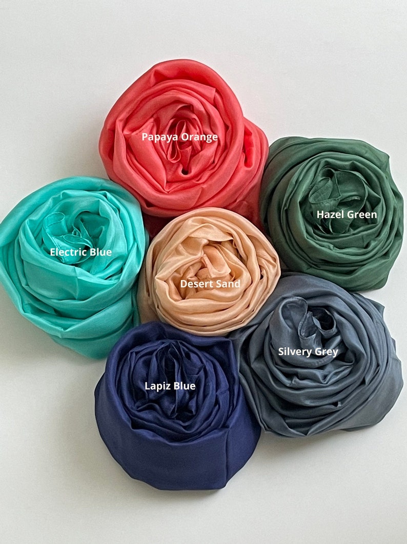 May include: Six rolled up fabric swatches in different colors: papaya orange, electric blue, desert sand, silvery grey, lapis blue, and hazel green.