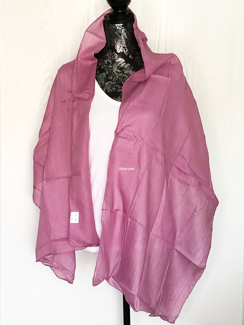 May include: A soft, sheer, onion pink scarf draped over a white shirt on a mannequin.
