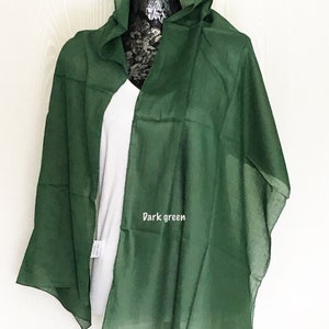 May include: A dark green sheer scarf draped over a white shirt on a mannequin. The scarf is made of a lightweight fabric and has a simple design.