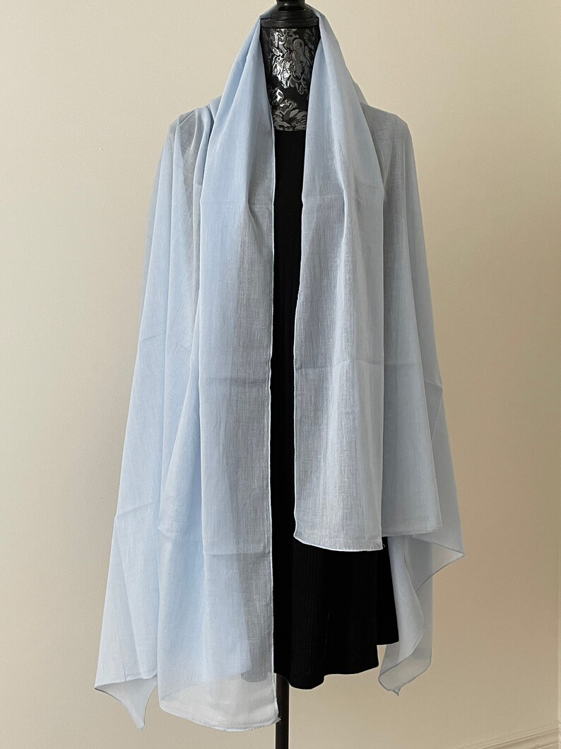 May include: A light blue sheer scarf draped over a black dress form.