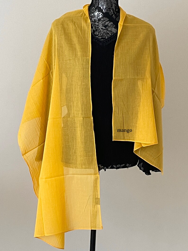 May include: A yellow sheer scarf with the word "mango" printed on it.