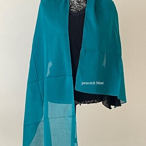 May include: A teal blue silk scarf with the words "peacock blue" printed on it.