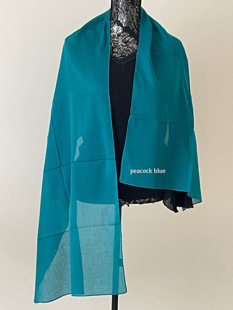 May include: A teal blue silk scarf with the words "peacock blue" printed on it.