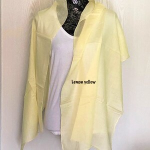 May include: A lemon yellow sheer scarf draped over a white mannequin. The scarf is made of a lightweight fabric and has a simple design.