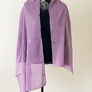 May include: A light purple sheer scarf draped over a mannequin. The scarf is made of a lightweight fabric and has a simple, elegant design.