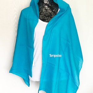 May include: A turquoise blue scarf draped over a mannequin. The scarf is made of a soft, lightweight fabric and has a simple, elegant design.