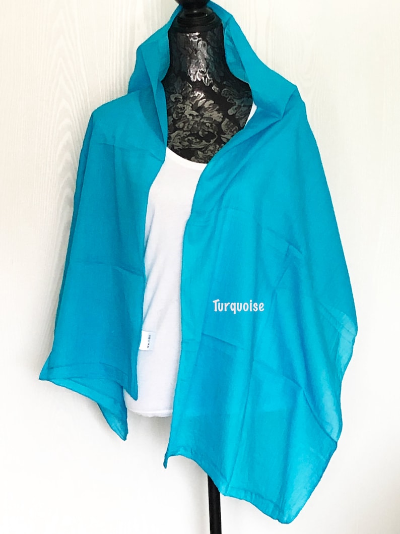 May include: A turquoise blue scarf draped over a mannequin. The scarf is made of a soft, lightweight fabric and has a simple, elegant design.