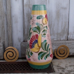 Peut inclure: Un vase en céramique avec un fond rose et un motif floral dans des tons de jaune, vert, rouge et bleu. Le vase a un col étroit et une base large.