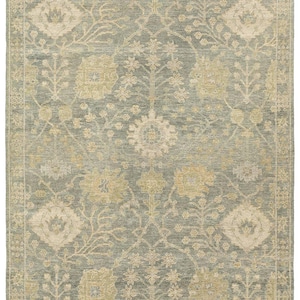 May include: A traditional style rug with a muted green background and a beige floral pattern. The rug has a border with a repeating pattern.