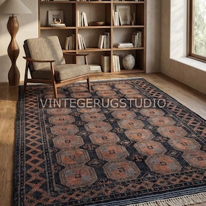 May include: A rectangular area rug with a geometric pattern in shades of navy blue, rust, and gray. The rug features a repeating design of squares and diamonds, with a fringed edge. The text "VINTAGERUGSTUDIO" is visible on the rug.