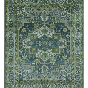 May include: A rectangular area rug with an intricate, symmetrical pattern in shades of teal, gray, and olive green. The design features floral and geometric motifs, with a detailed border. The rug is suitable for living rooms and bedrooms.