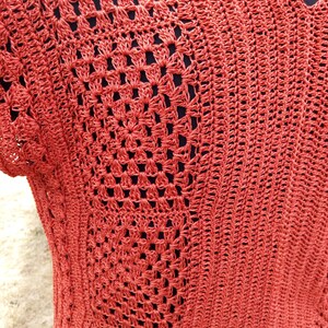 Może przedstawiać: Zbliżenie na dzianinowy top z fakturowanym wzorem o otwartych oczkach. Top jest w żywym pomarańczowym kolorze.