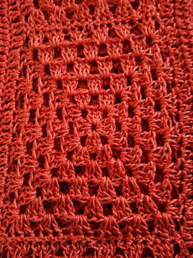 Może przedstawiać: Zbliżenie na czerwoną tkaninę wykonaną na szydełku z powtarzającym się wzorem kwadrat&oacute;w i romb&oacute;w.