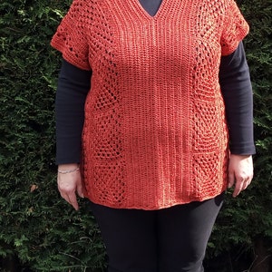 Könnte beinhalten: Ein gehäkeltes Oberteil mit V-Ausschnitt und kurzen Ärmeln. Das Oberteil ist rostbraun und hat ein Spitzenmuster.