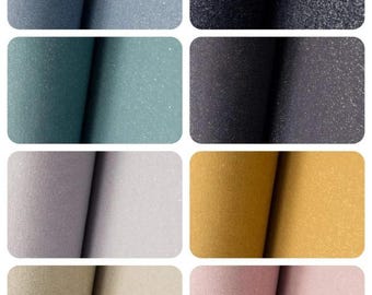 Op de afbeelding: Een verzameling van tien stofstalen in verschillende kleuren, waaronder blauw, groen, paars, geel en roze. Elk staal heeft een subtiel glinsterend of glimmende effect.