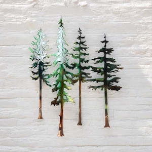 May include: Four metal pine trees in shades of green and brown, mounted on a white wall. The trees are stylised and have a rustic, vintage look.