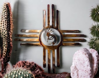 May include: A metal wall art piece in the shape of a Zia symbol with a stylized Native American dancer in the center. The symbol is made of gold metal and has a rustic, weathered look.