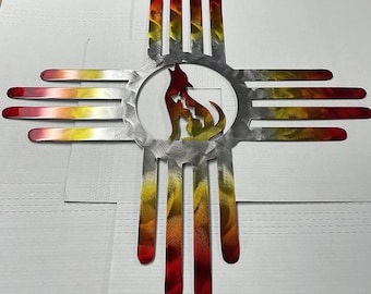 May include: A metal wall art piece in the shape of a Zia symbol with a howling wolf in the center. The Zia symbol is painted in shades of red, orange, and yellow. The wolf is silhouetted in a silver circle.