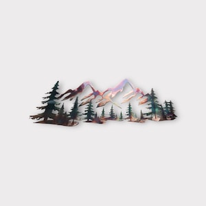 May include: Metal wall art depicting a mountain range with a forest of evergreen trees in the foreground. The mountains are a gradient of pink, purple, and blue, while the trees are a dark green.