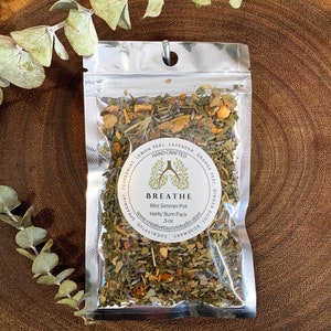 May include: A silver pouch filled with dried herbs and spices for a mini simmer pot. The label reads "BREATHE Mini Simmer Pot Herb/Burn Pack 5 oz www.creativetaurusstudio.store Rosemary, Eucalyptus, Ginger Root, Orange Peel, Lavender, Lemon Peel, Peppermint, Spearmint"