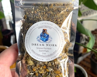 Puede incluir: Una bolsa de plástico transparente llena de hierbas y flores secas, etiquetada como Dream Work Simmer Pot Herb Scent Pack. La etiqueta muestra una ilustración de una botella de poción azul y enumera ingredientes como lavanda, jazmín y manzanilla. Pesa 14g.
