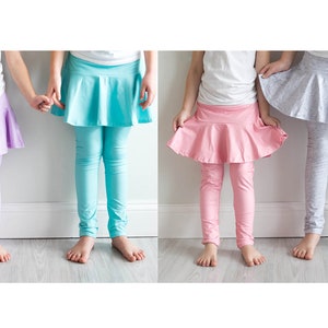 May include: Four girls wearing leggings with attached skirts in different colors: lavender, turquoise, pink, and gray.