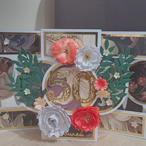 Può includere: Un biglietto bianco con un numero 50 dorato. Il biglietto è decorato con fiori e foglie. Il biglietto è un biglietto pop-up e ha un effetto 3D. Il biglietto dice "Happy 50th Birthday" sul davanti.